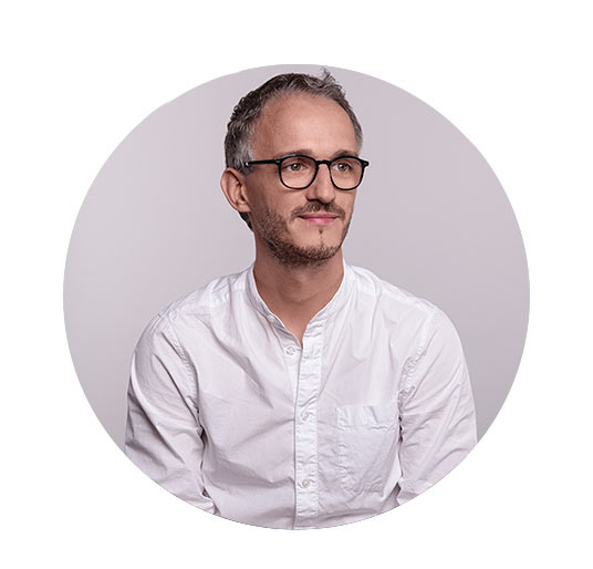 Portrait des Mitarbeiters Christoph vor grauem Hintergrund
